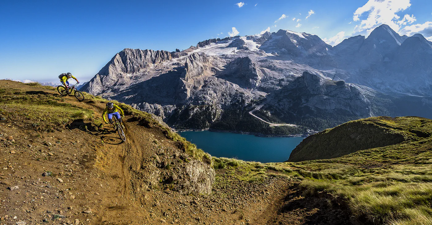 Mountain biker sui sentieri dolomitici, con il lago e le montagne sullo sfondo