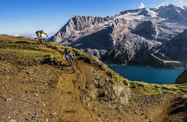 Mountain biker sui sentieri dolomitici, con il lago e le montagne sullo sfondo